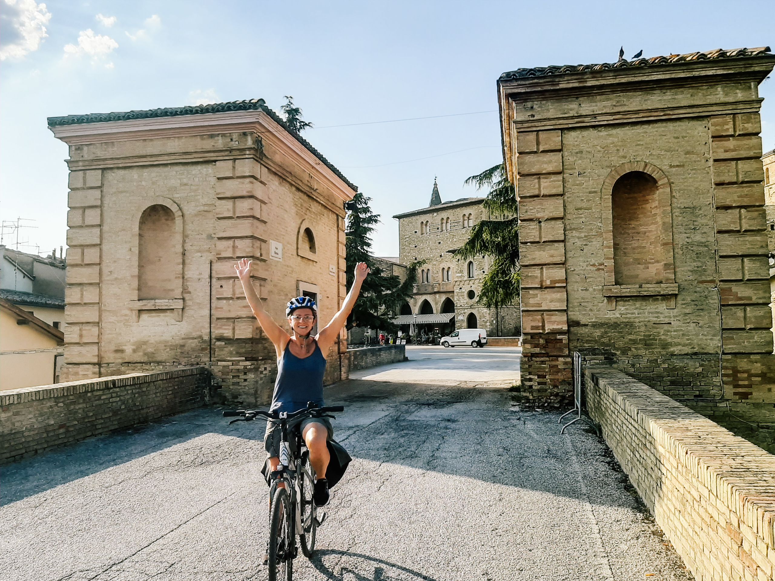 Ciclista in viaggio con "Girolibero", vista di un borgo antico con edifici in pietra e vicoli a Spello, Umbria